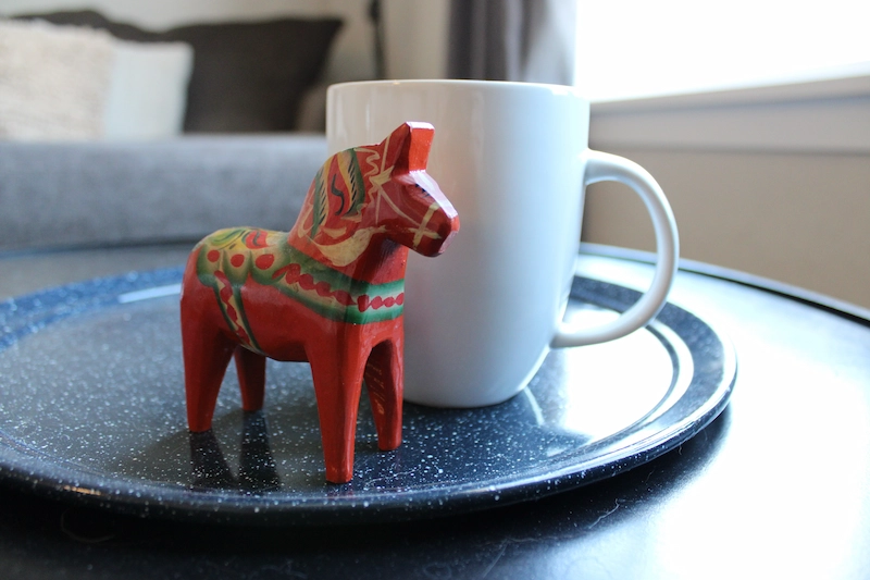 Röd gammal dalahäst placerad på ett fat med en kaffekopp